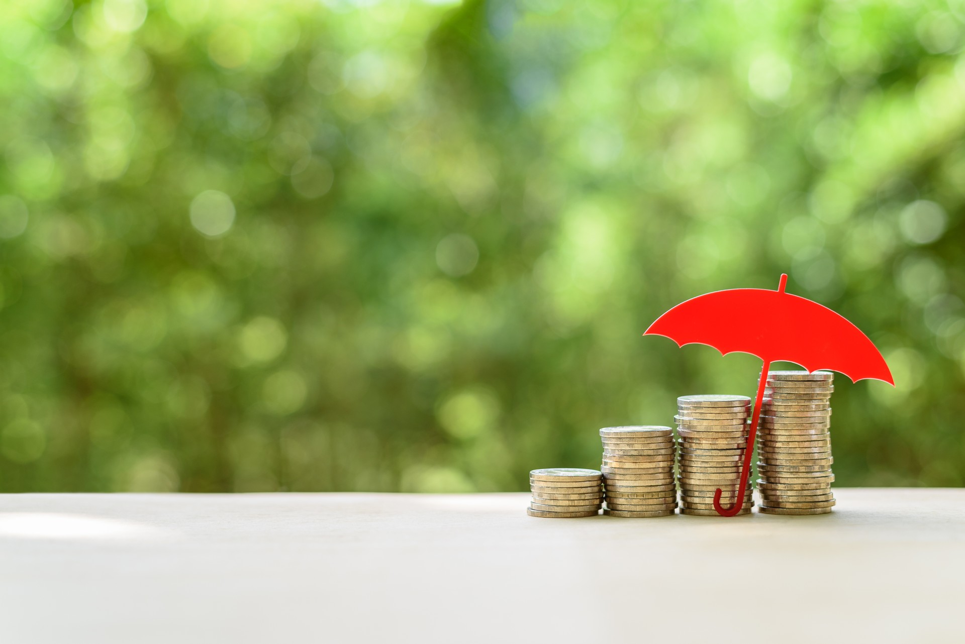 Red umbrella protects coins or cash on a table