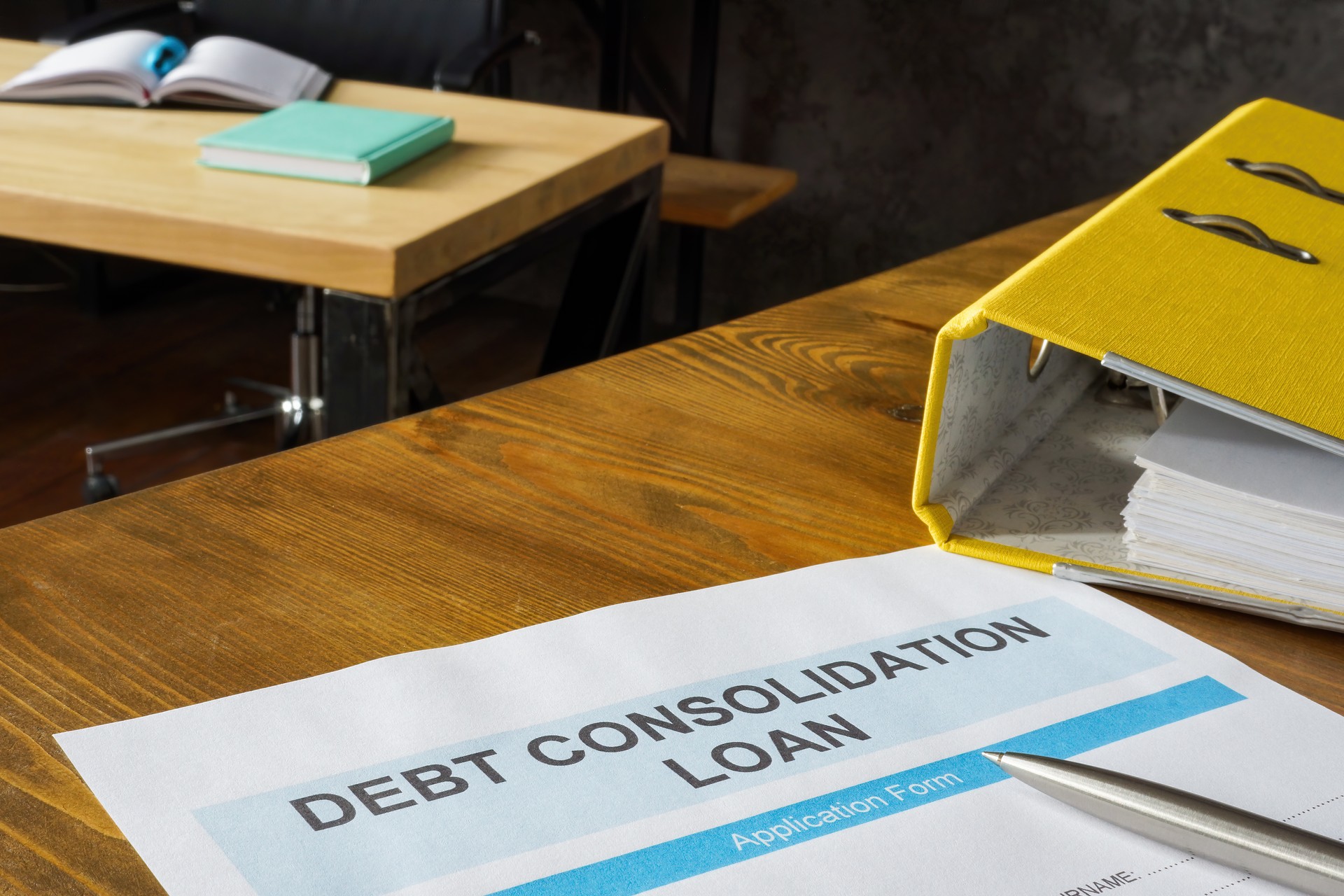 Debt consolidation loan application near yellow folder.